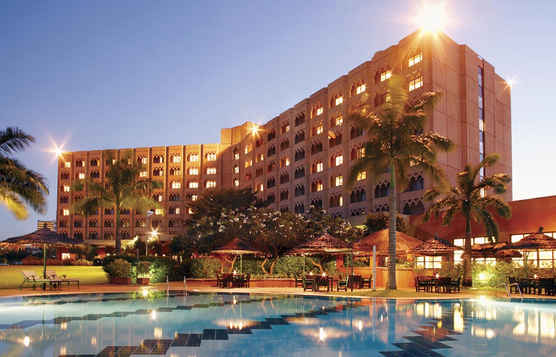 The Dar Es Salaam Serena Hotel in Tanzania at dusk above a swimming pool with palm trees surrounding it