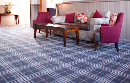 Hotel waiting room with a blue and white checked flooring, a sofa and a wooden coffee table